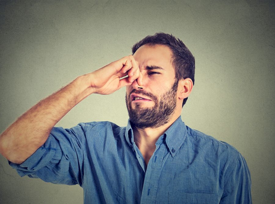 disgusted man pinches nose with fingers hands looks with disgust something stinks