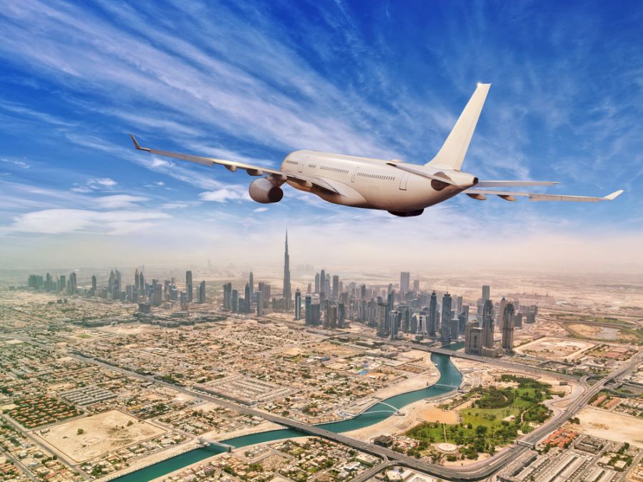 Commercial airplane flying above Dubai city