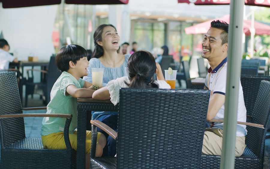 Asian family smiling, eating & drinking outdoor at streetside table