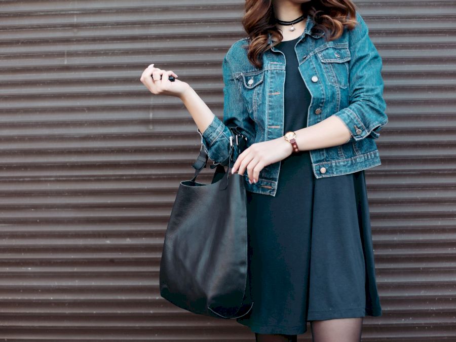 Stylish incognito girl posing at street with black leather bag.