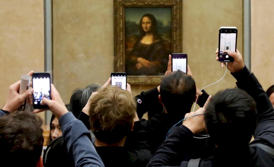 FILE PHOTO: Visitors take pictures of the painting "Mona Lisa" by Leonardo Da Vinci at the Louvre museum in Paris